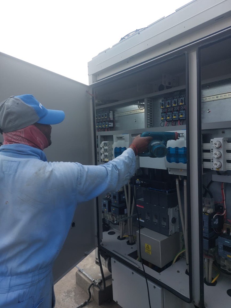Technician working inside an electrical control panel