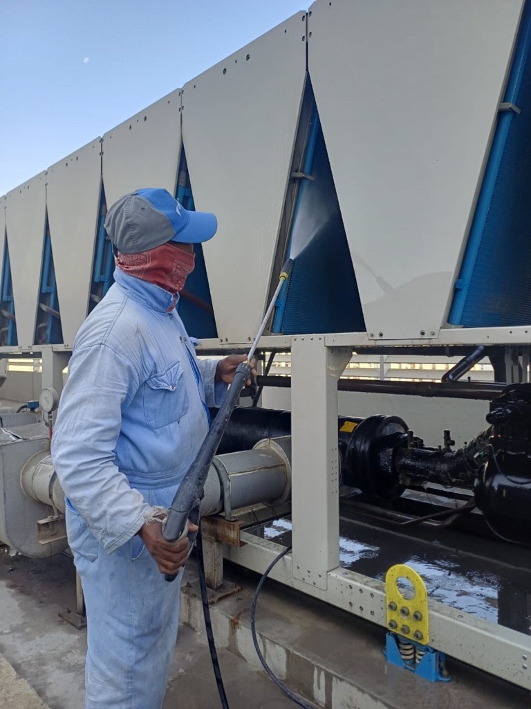 Technician pressure-washing a chiller condenser coil