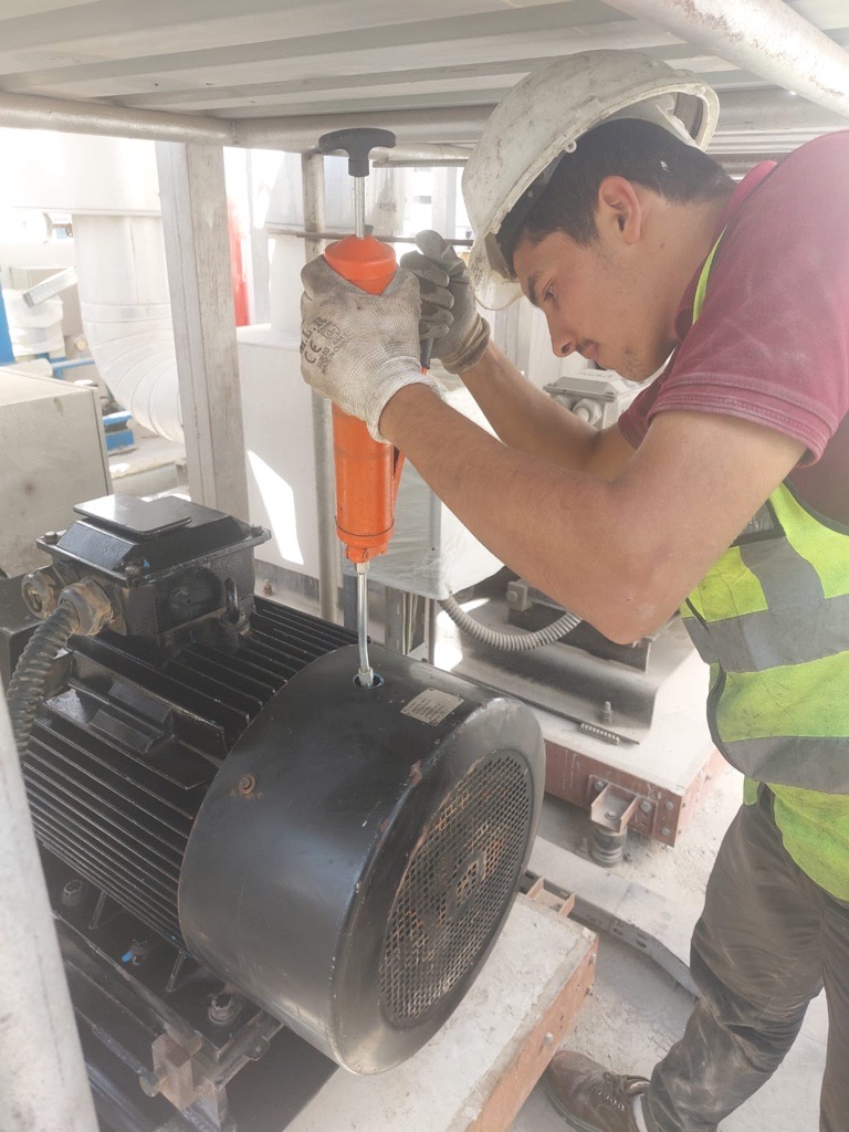 Technician lubricating an electric motor and pump
